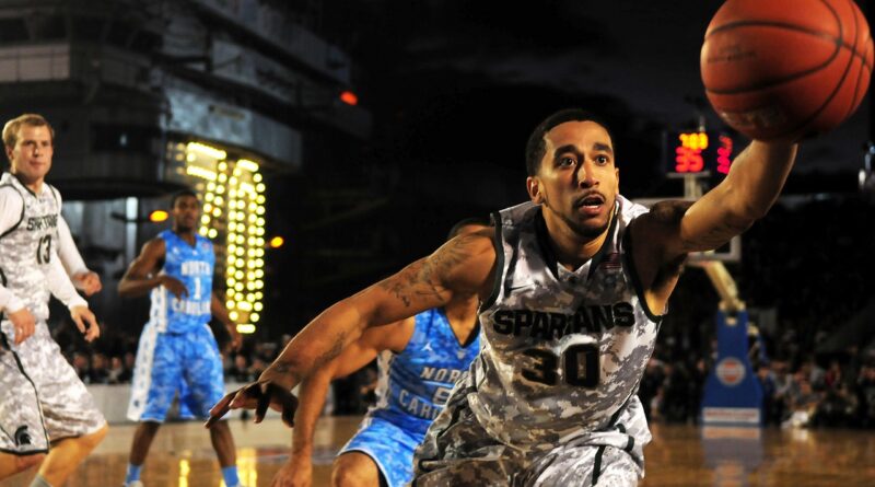 Un jugador de bàsquet es llença per agafar una pilota que està a punt de marxar per la línia de fons